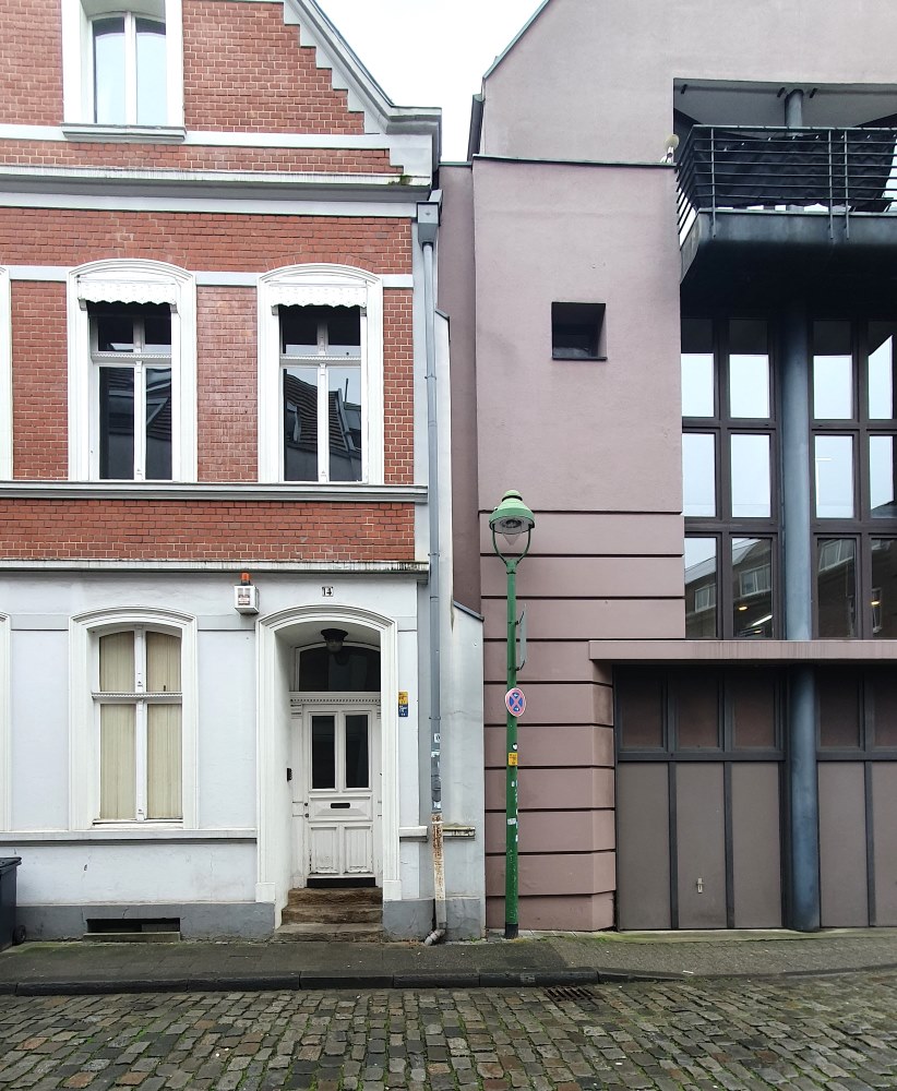 Straßenansicht von zwei Häusern. Links ein Altbau, rechts ein Neubau